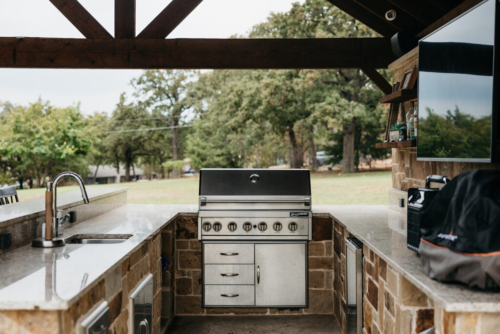 Stone Outdoor Kitchen with Bar Seating in Gunter TX